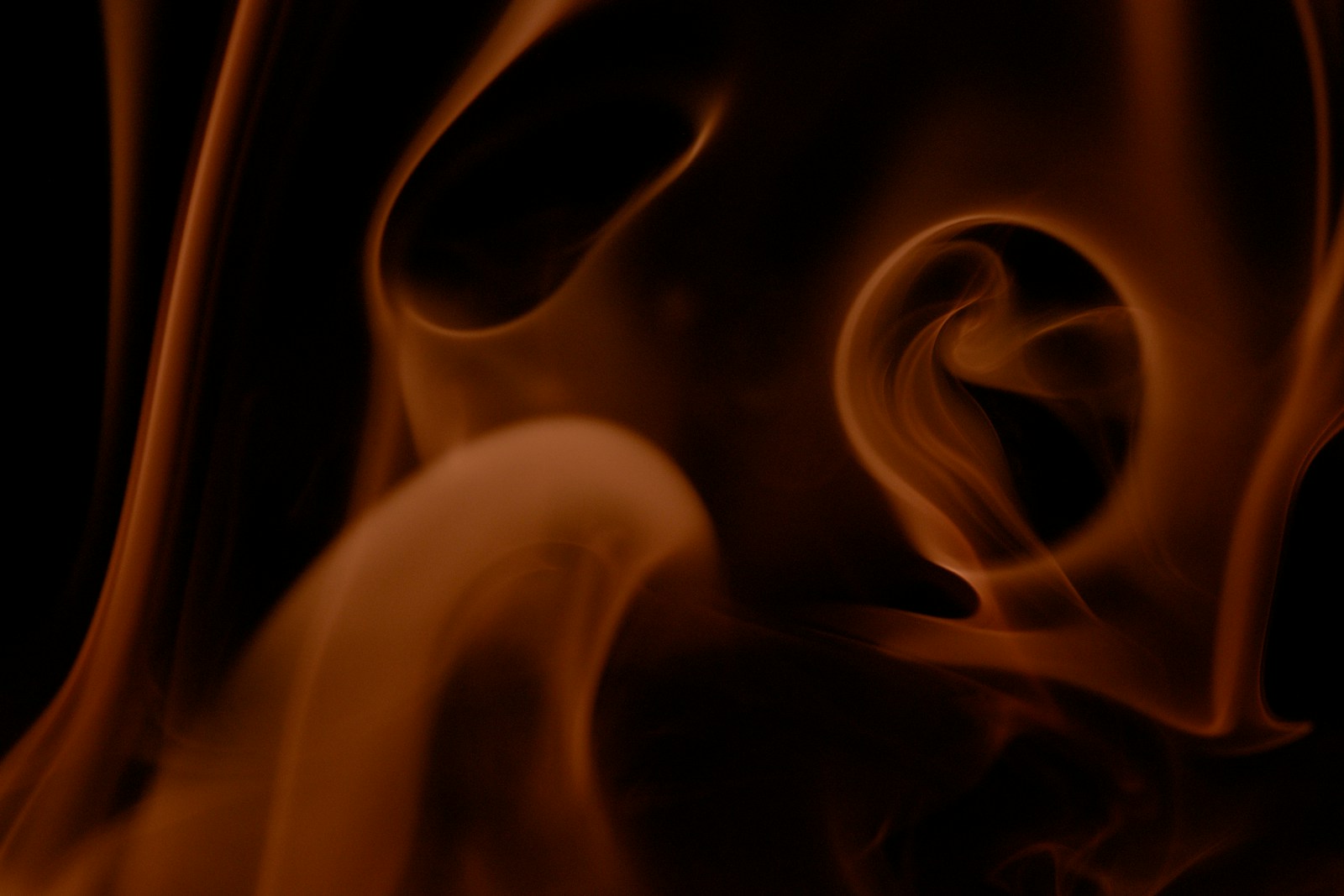 Abstract swirling orange smoke against black background