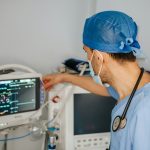 a man in scrubs and a stethoscope looking at a monitor